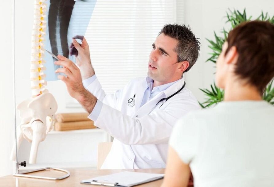 El médico examina una radiografía para diagnosticar la osteocondrosis torácica.